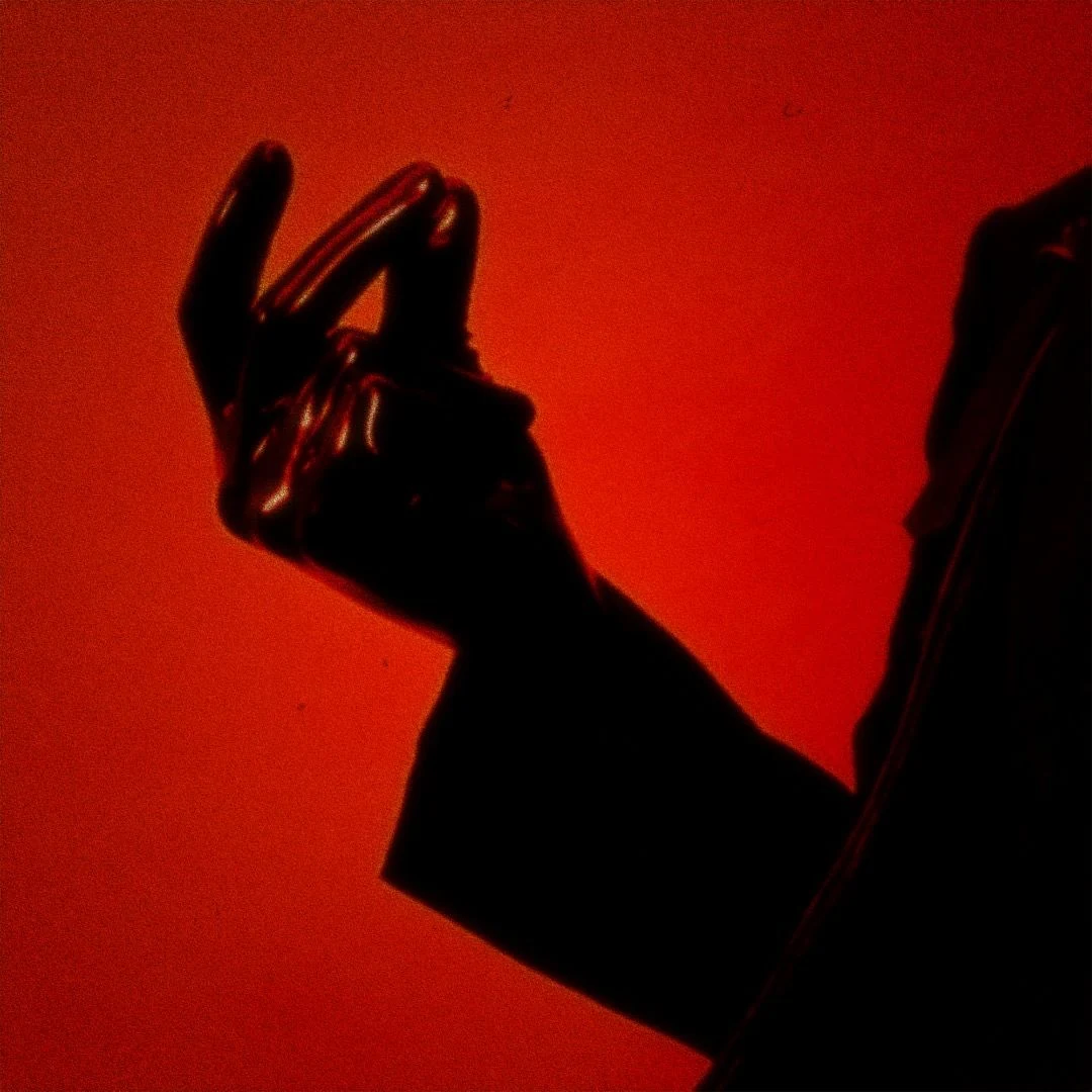 Black-gloved hand poised against a deep red background — The Ruler